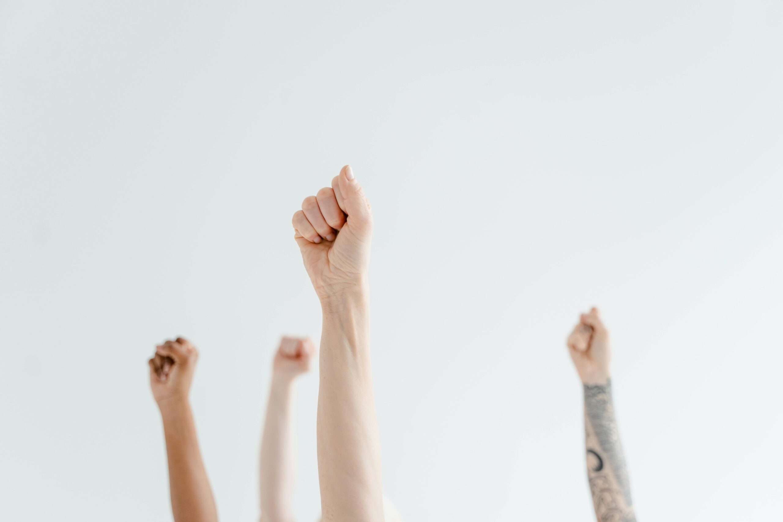 Vier Hände zu Fäusten richtung Himmel